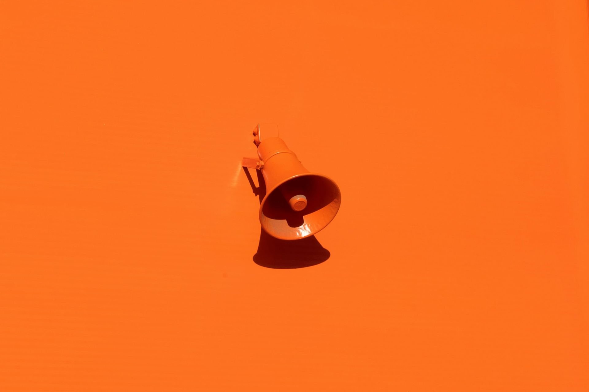 Orange speakerphone attached to an orange wall